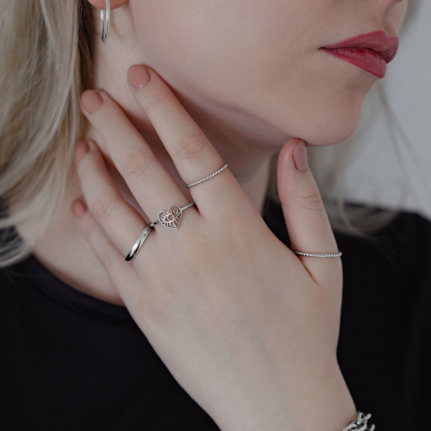 Frau trägt mehrere Ringe, darunter ein Eye Ring in Silber auf hellem Hintergrund