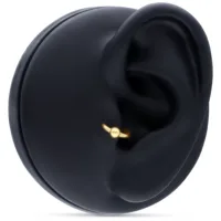 Goldener Klemmkugelring in Ohrpiercing auf schwarzem Hintergrund