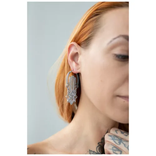 Frau mit Khamsa Hoops Ohrringen aus Chirurgenstahl in Silber auf hellem Hintergrund