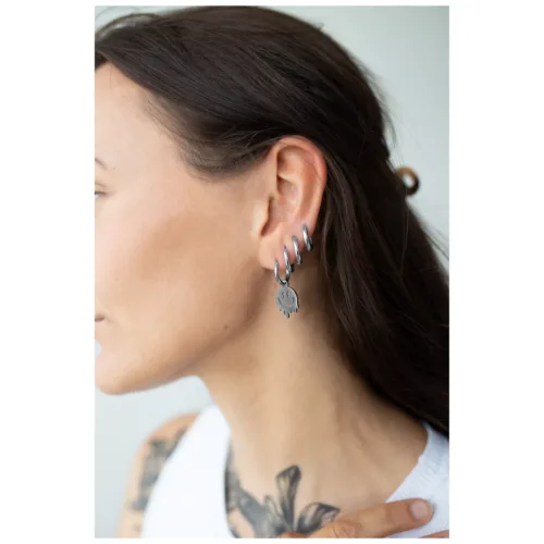 Frau mit langen Haaren trägt silberne Little Smiley Hoops an ihrem Ohr.