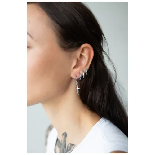 Silberne Ohrringe in Schwertform an weiblichem Ohr auf neutralem Hintergrund
