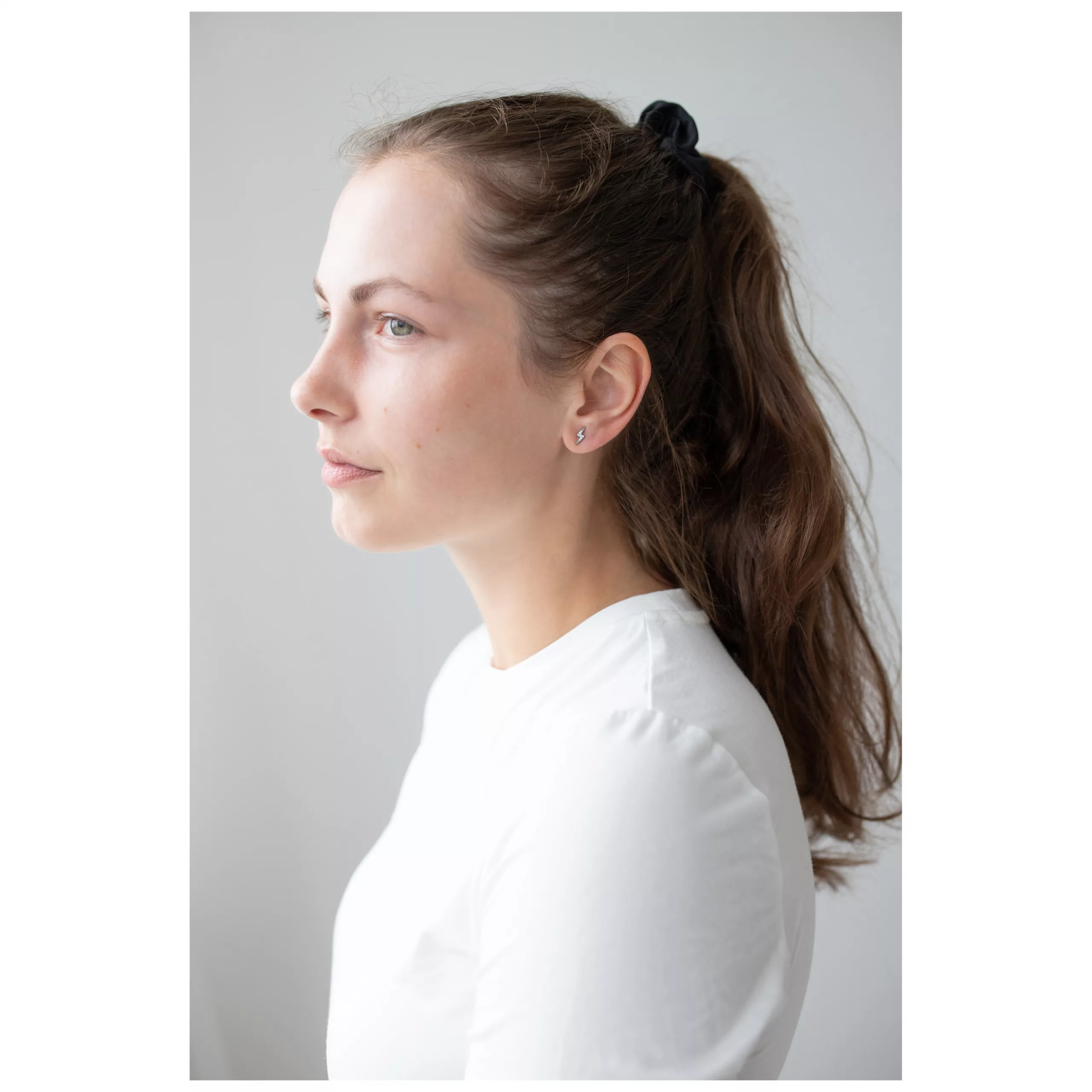 Frau mit langen Haaren trägt silberne Crystal Lightning Ohrstecker.