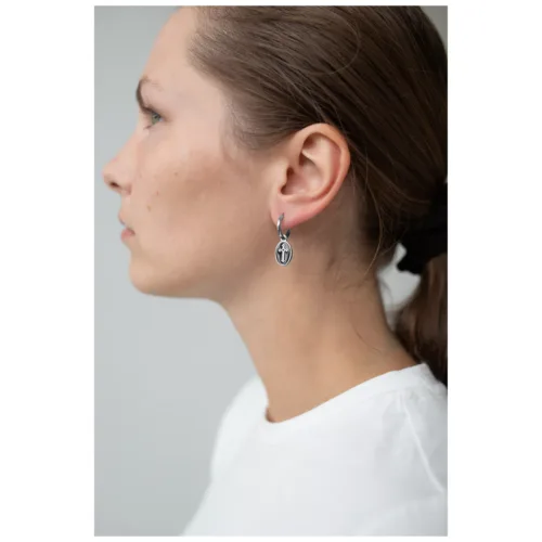 Seitliche Ansicht einer Frau mit silbernen Kreuz-Ohrringen auf hellem Hintergrund