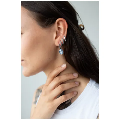 Silberne Schlangen-Ohrringe am Ohr einer Frau auf hellem Hintergrund