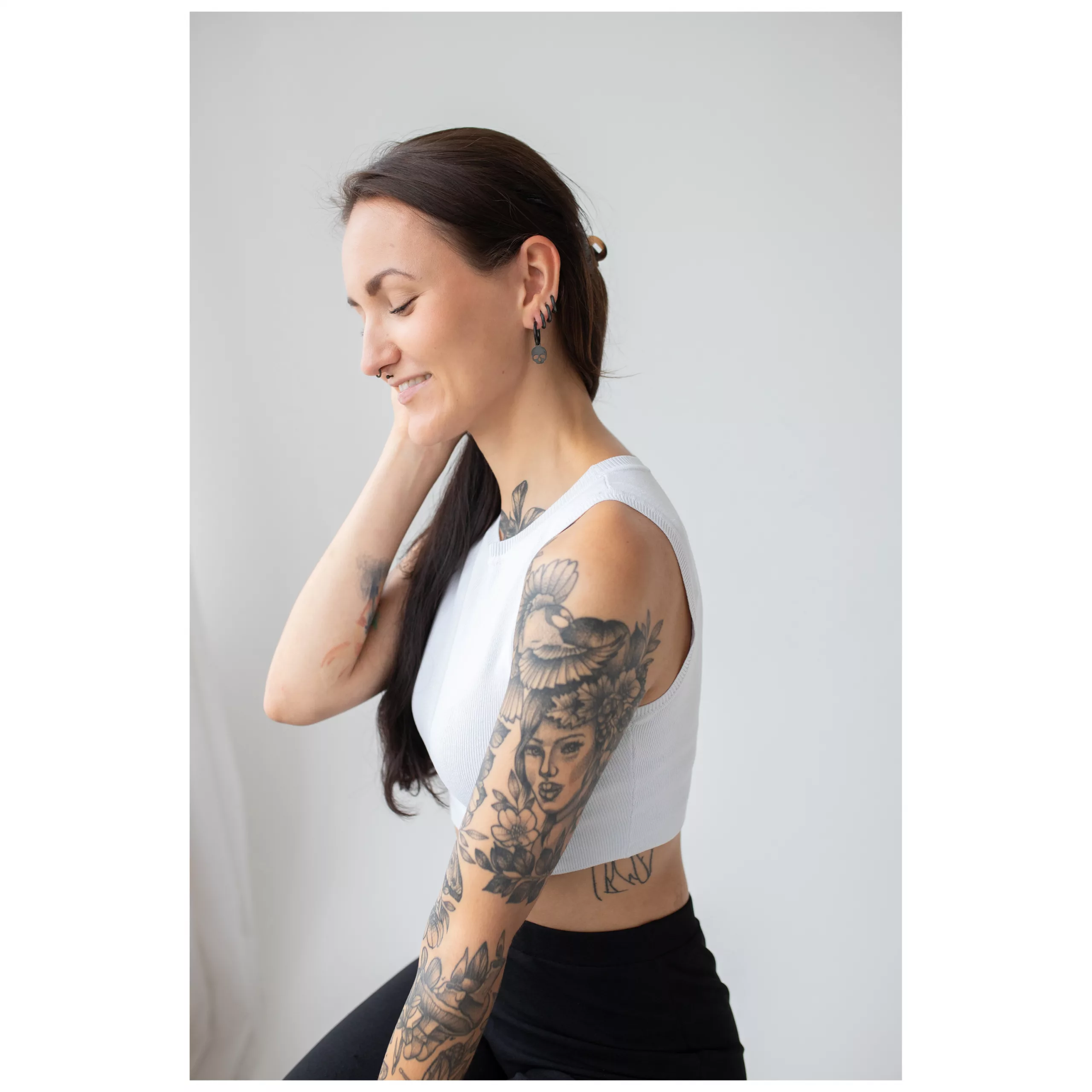 Frau mit langen Haaren trägt schwarze Skull-Ohrringe vor hellem Hintergrund