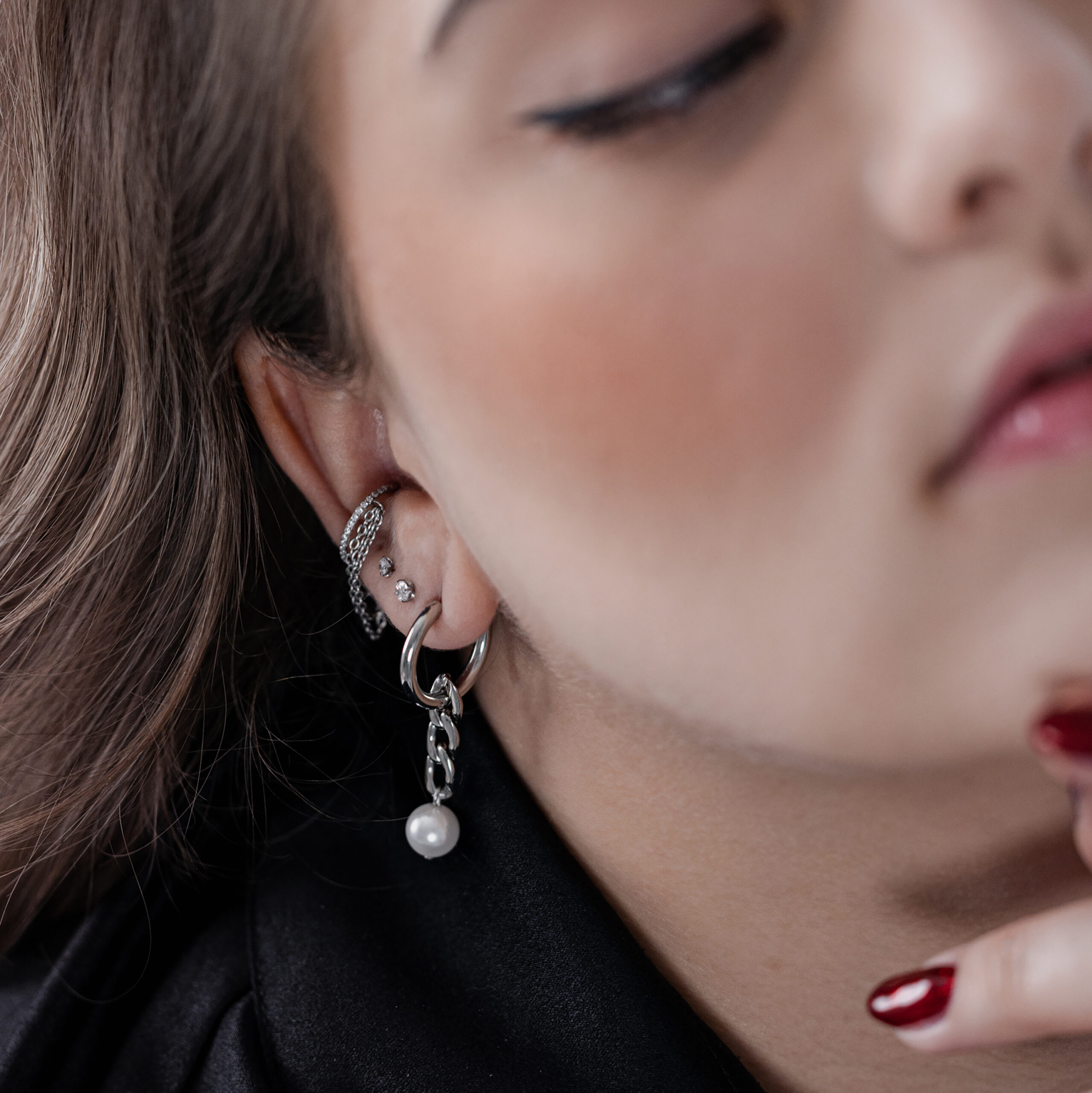 Silberne Ohrringe mit Perlenanhänger Nahaufnahme von Silber Creolen mit Perlenanhänger am Ohr einer Person