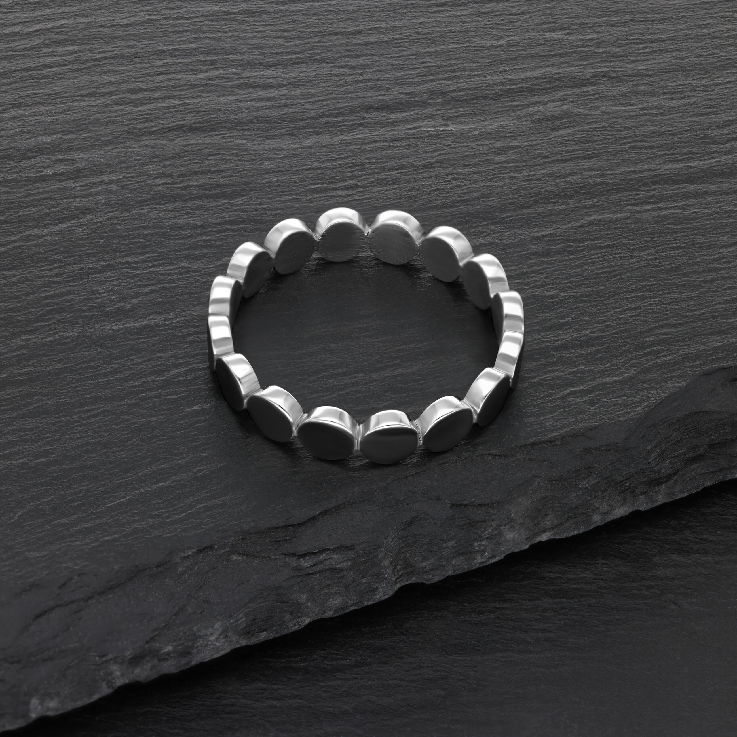 Silberner Plattenring aus Chirurgenstahl auf schwarzem Schieferhintergrund