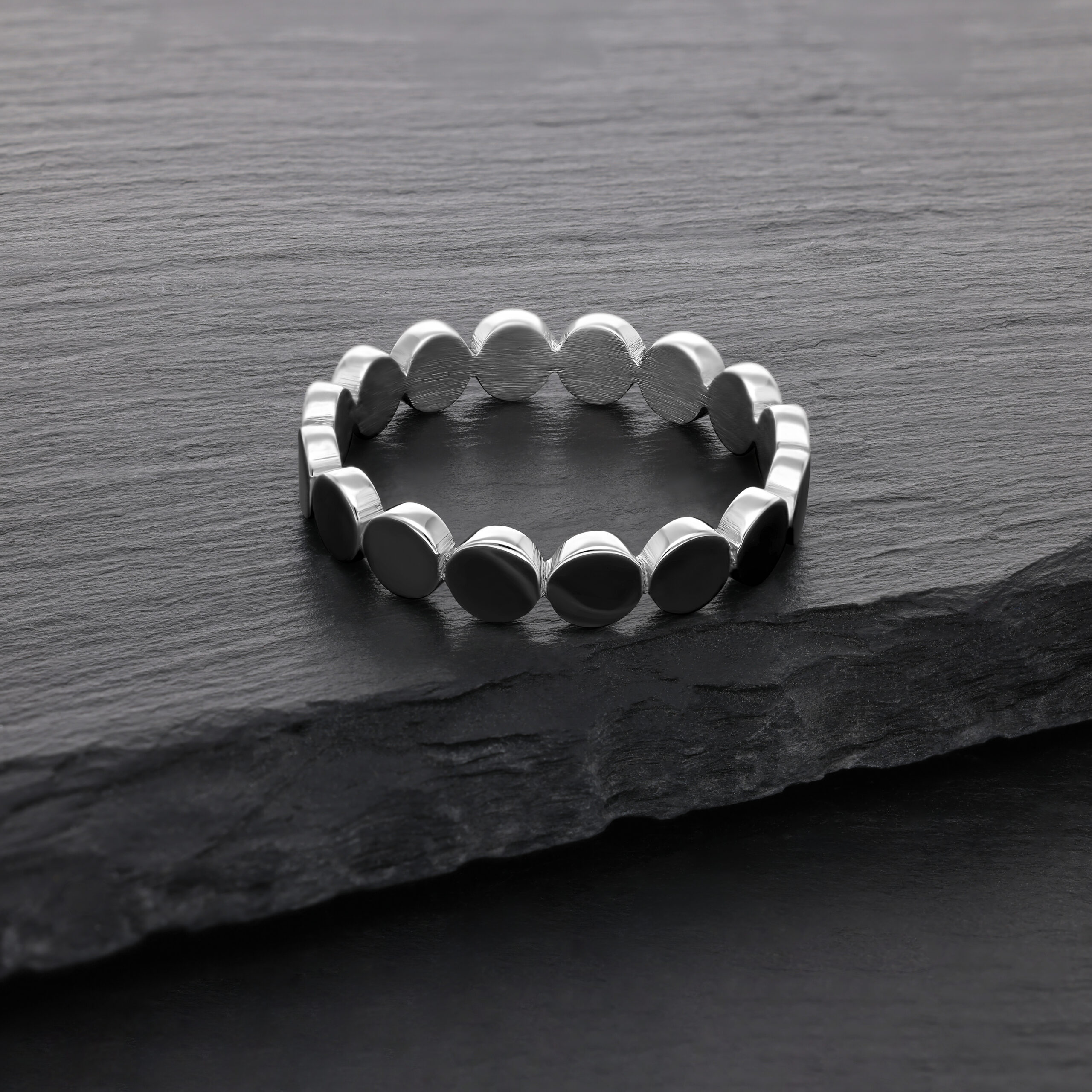 Silberner Ring aus Chirurgenstahl auf dunkler Steinoberfläche