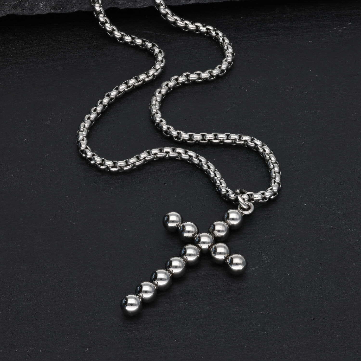 Silberne Kreuzkette mit Kugeldesign auf schwarzem Hintergrund