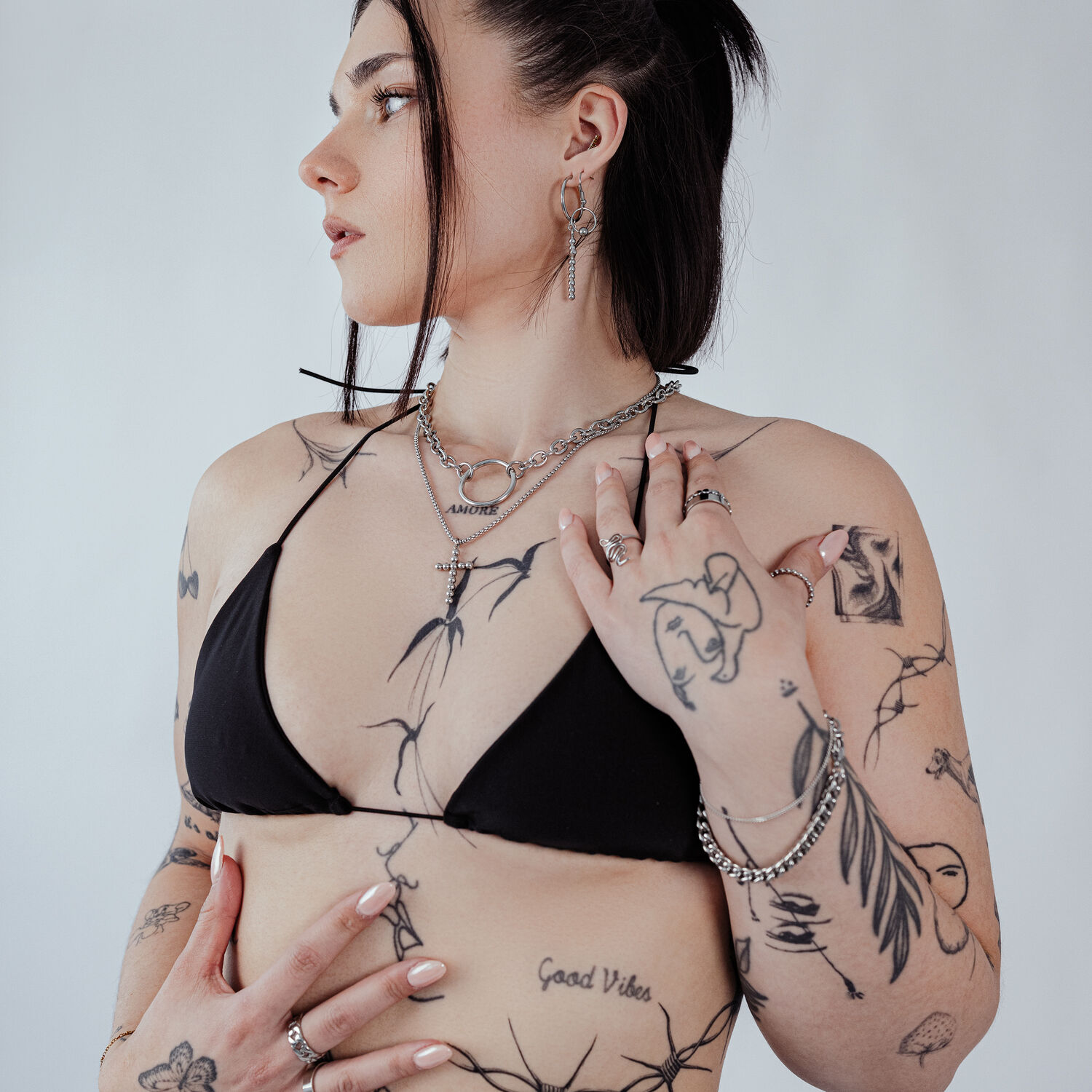 Frau mit Bubble Cross Kette aus Chirurgenstahl in Schwarz und Silber auf weißem Hintergrund