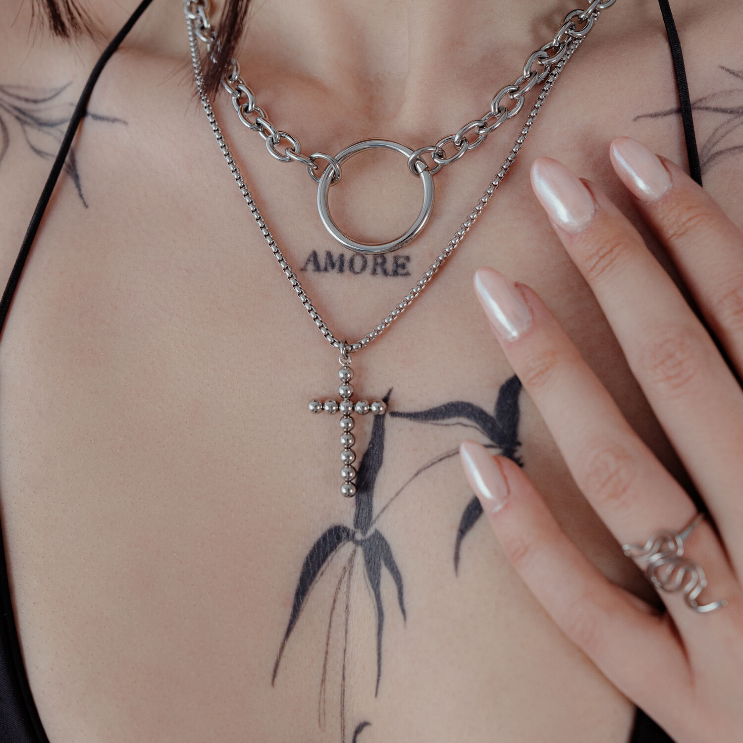 Silberne Bubble Cross Halskette an einer Frau mit Tattoos, Nahaufnahme