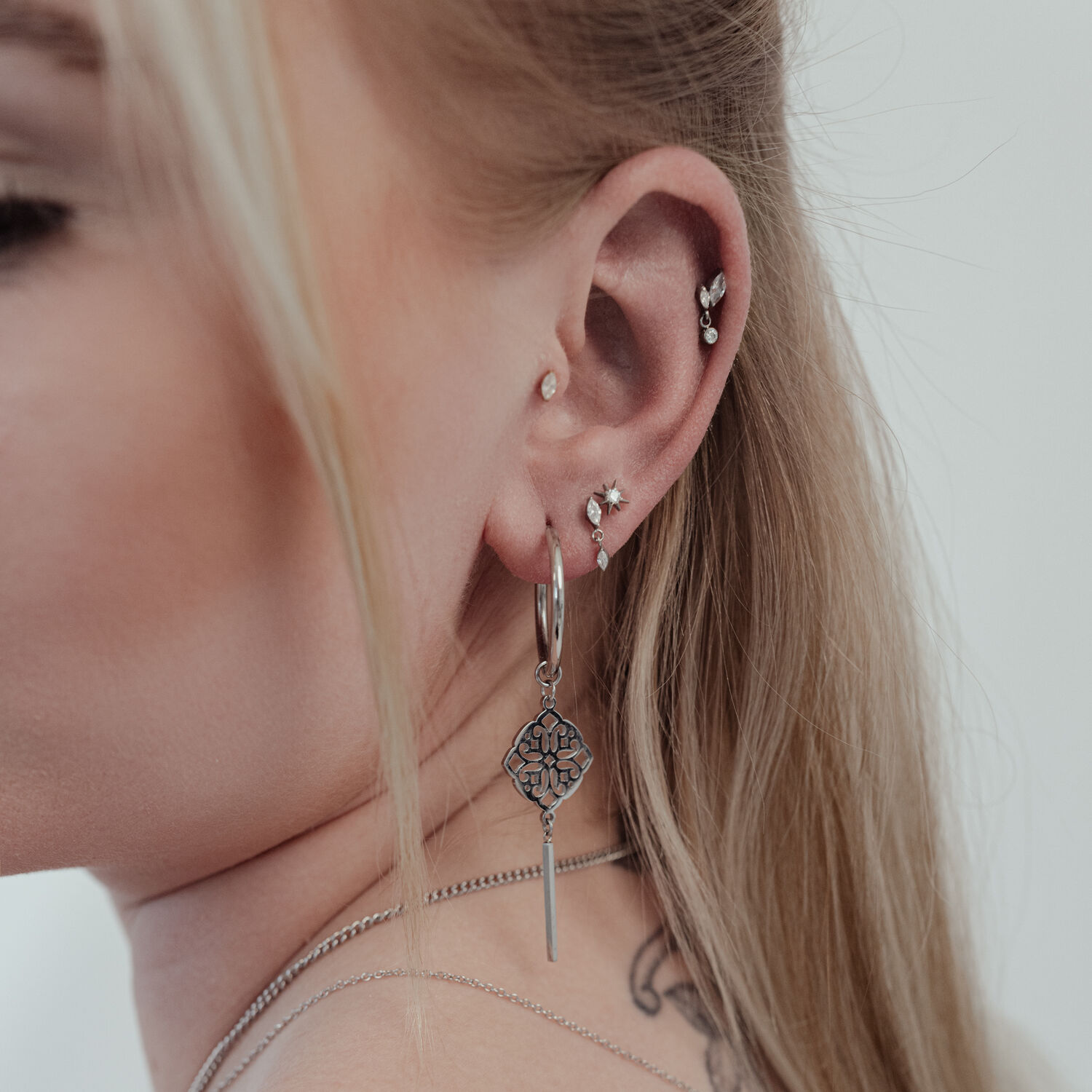 Nahaufnahme eines Ohres mit mehreren Piercings, darunter ein großer, silberner Push Fit Kristall Stern Aufsatz.