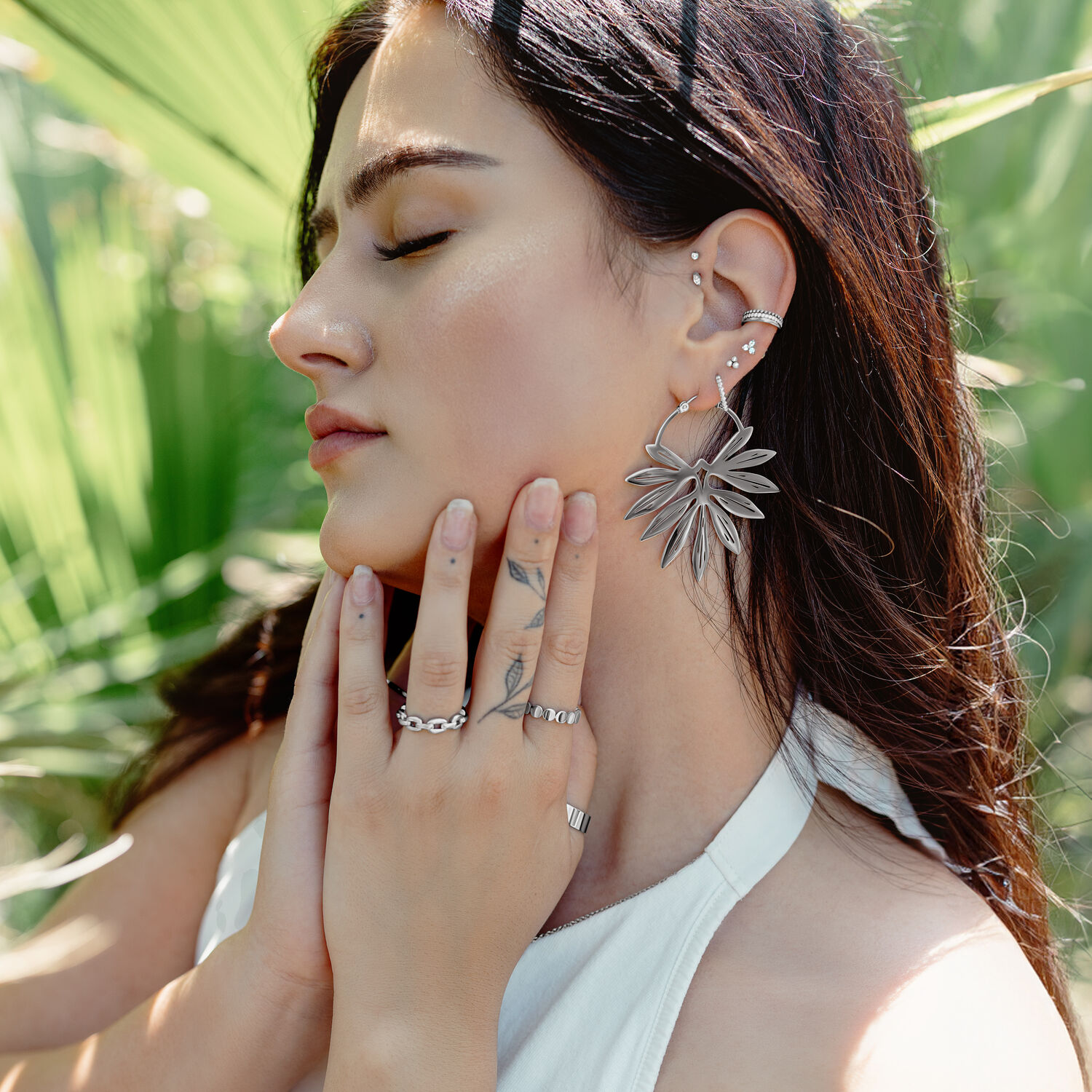 Bamboo Hoops Paar in Schwarz und Gold Frau mit eleganten Bambus-Ohrringen in Schwarz und Gold vor grünem Hintergrund