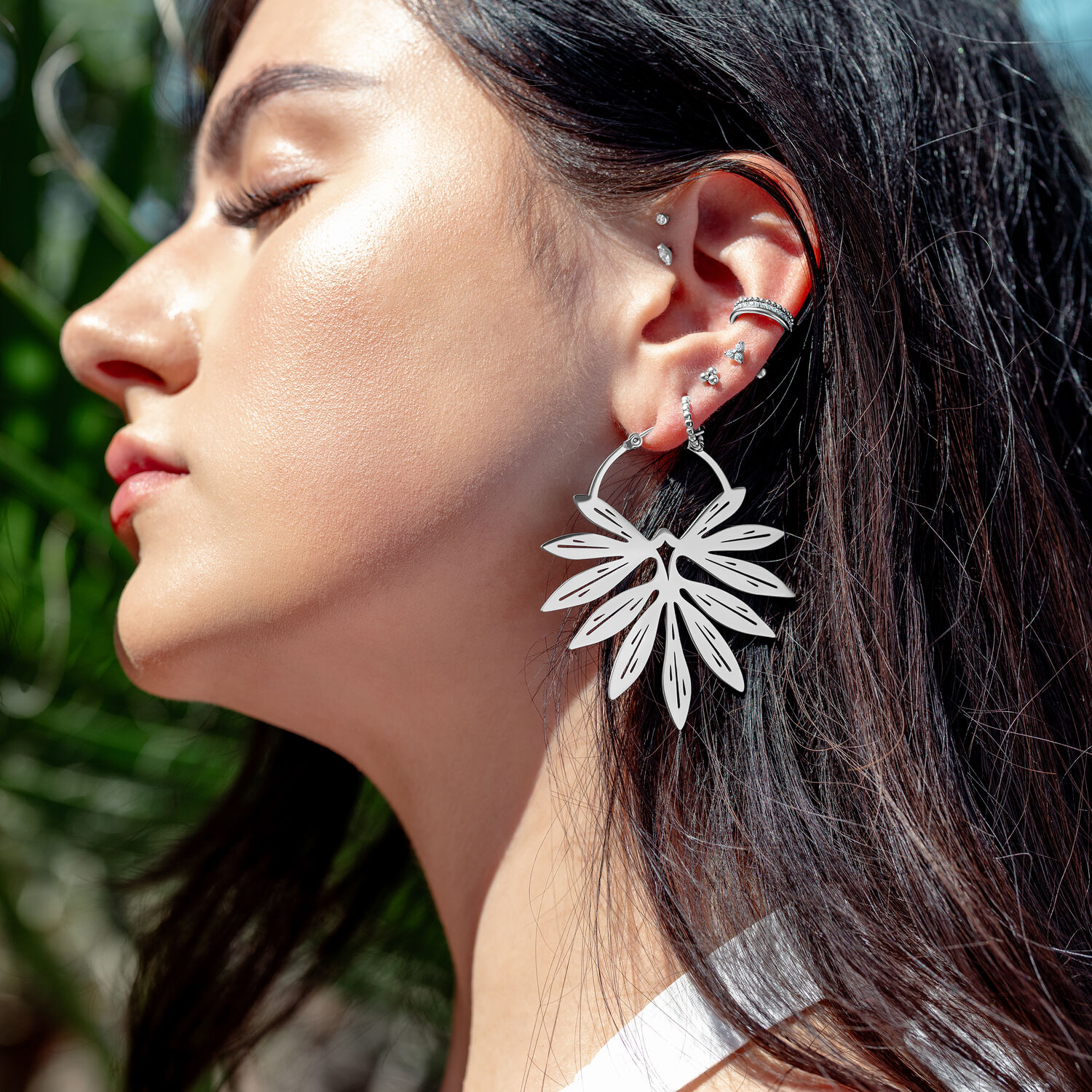 Elegante Bambus-Ohrringe in Silber Nahaufnahme einer Frau mit silbernen Bambus-Ohrringen im Sonnenlicht