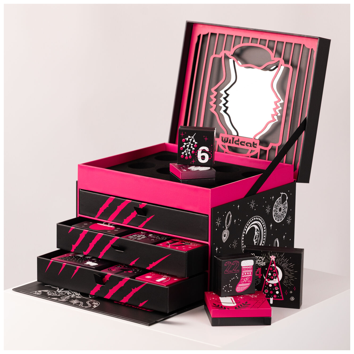 Schwarzer Wildcat Adventskalender mit offenen Schubladen und pinken Akzenten auf weißem Hintergrund