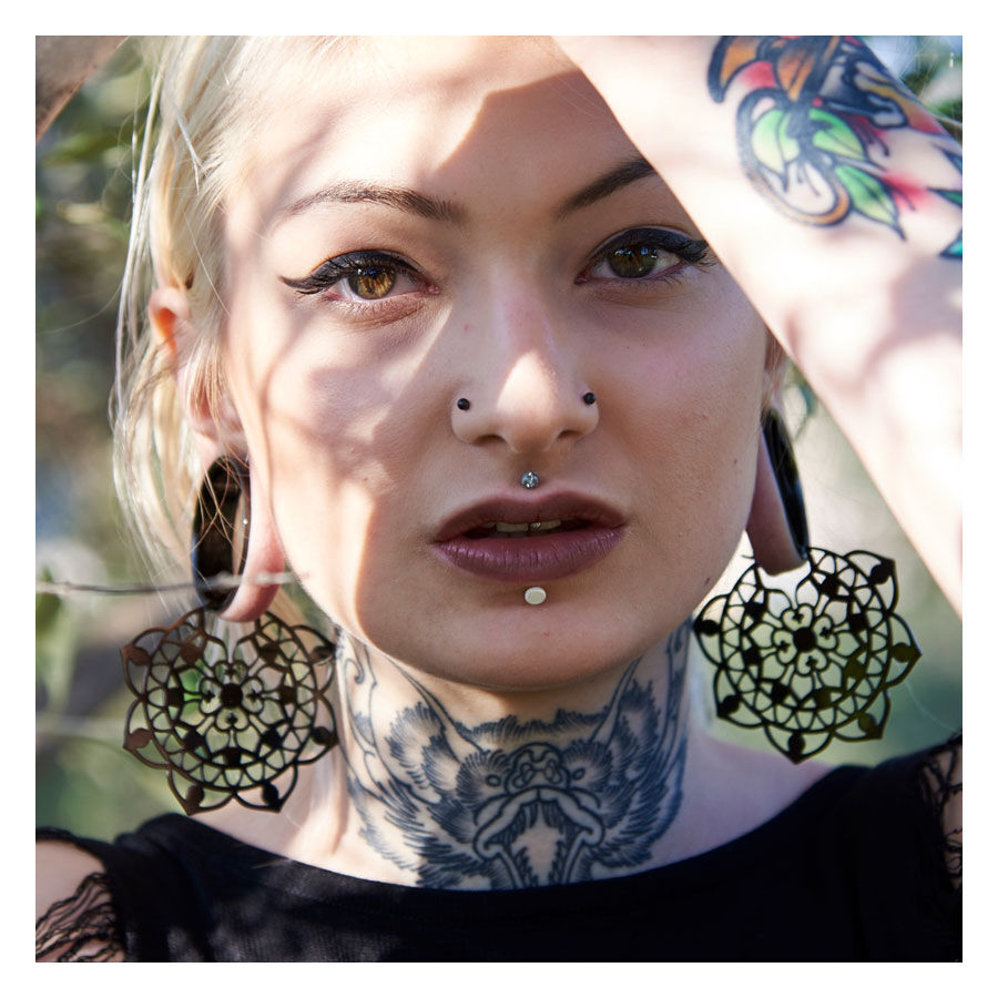 Frau mit großen schwarzen floralen Ohrringen aus Chirurgenstahl