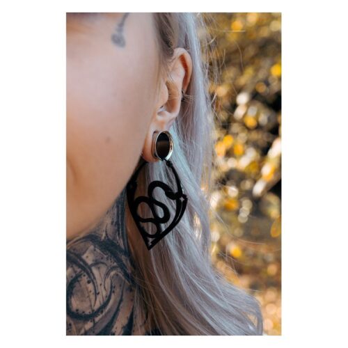 Nahaufnahme eines Ohres mit schwarzen Snake Hoops Ohrringen, Hintergrund unscharf