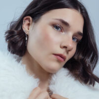 Eleganter Ohr-Piercing Aufsatz mit Schleife Frau mit elegantem Push Fit Piercing Aufsatz in Silber an der Ohrmuschel, weißer Hintergrund