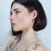 Seitenansicht einer Frau mit mehreren Ohrringen, darunter ein Push Fit Aufsatz mit Kristallen, vor hellem Hintergrund