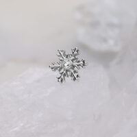 Silberner Schneeflocken-Piercingaufsatz mit klarem Kristall auf weißem Hintergrund