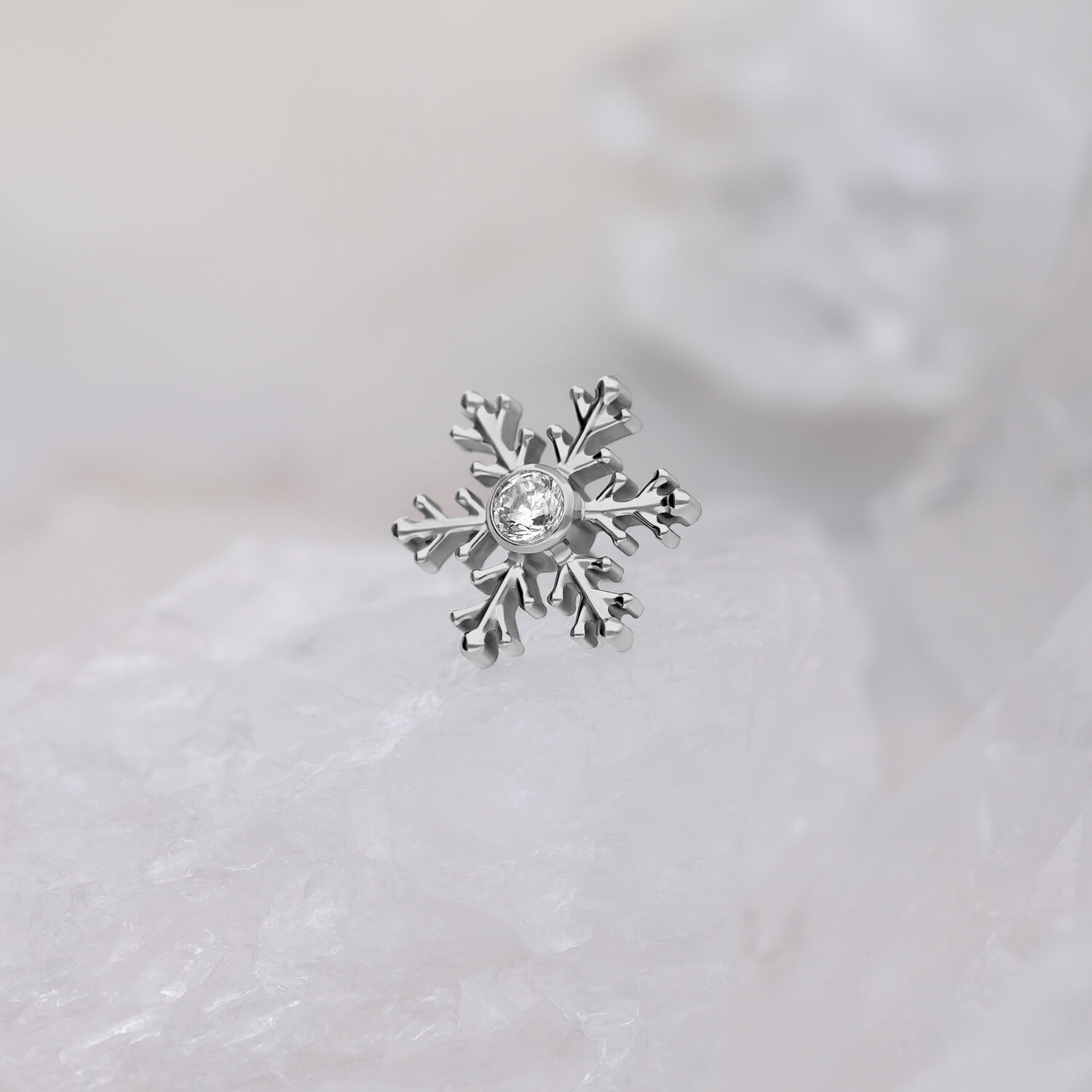 Silberner Schneeflocken-Piercingaufsatz mit klarem Kristall auf weißem Hintergrund