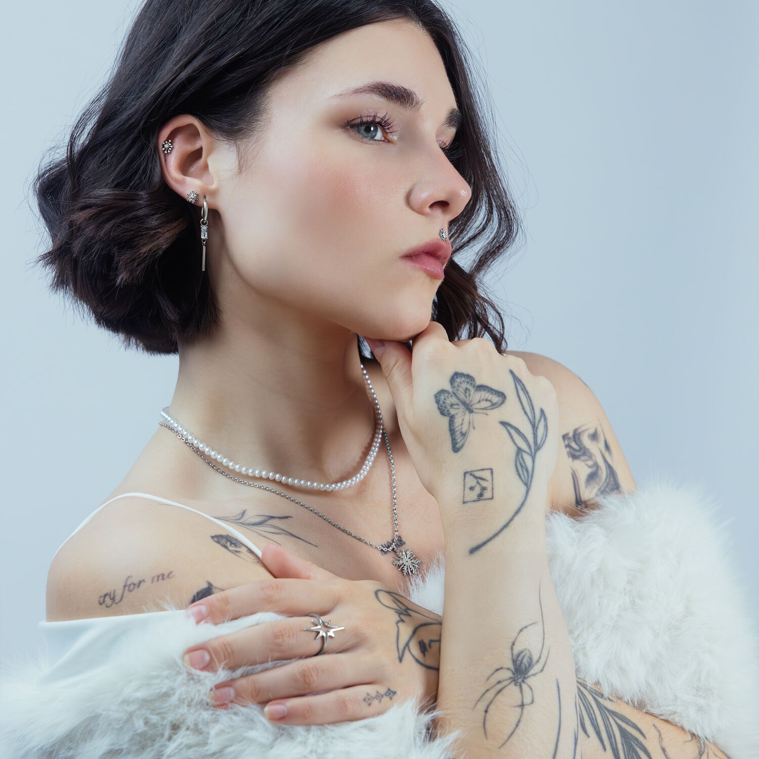 Frau mit mehreren Piercings, darunter ein silberner Sunburst Aufsatz im Ohr, vor neutralem Hintergrund