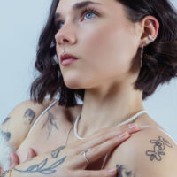 Frau mit mehreren Piercings, Kristallaufsatz im Ohr, stilvoller Look