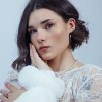 Silberner Push Fit Stern Aufsatz am Ohr Frau mit kurzem Haar trägt silbernen Push Fit Stern Aufsatz im Ohr, vor weißem Hintergrund