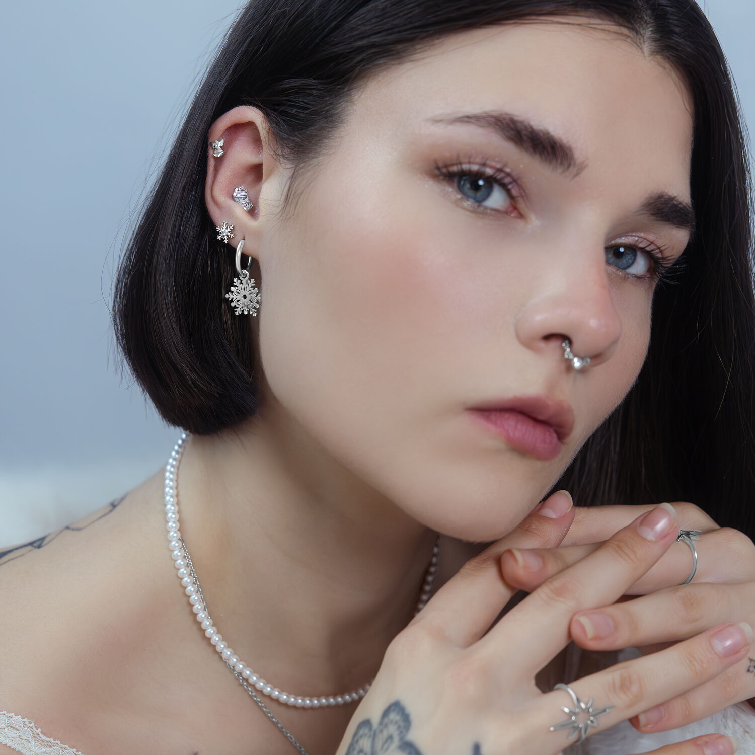 Frau mit mehreren Piercings, darunter ein silberner Snow Angel Aufsatz im Ohr, auf neutralem Hintergrund.