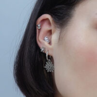 Frau mit silbernem Snow Angel Piercing am Ohr, Hintergrund neutral