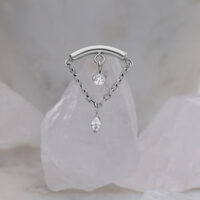 Silberner Helix-Aufsatz mit zwei klaren Kristallen auf marmoriertem Hintergrund