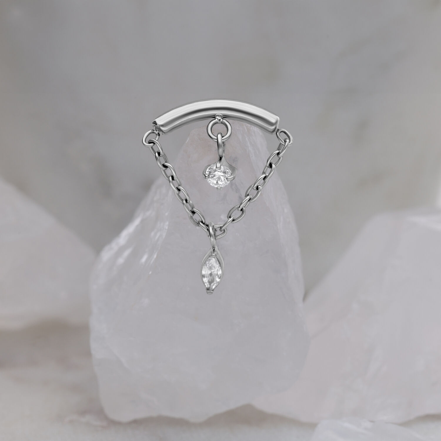 Silberner Helix-Aufsatz mit zwei klaren Kristallen auf marmoriertem Hintergrund