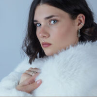 Frau mit helix Piercing und silbernem, doppeltem Schmuckaufsatz vor hellem Hintergrund