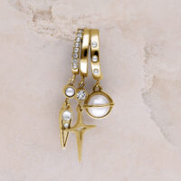 Drei goldene Ohrstecker mit Perlen, Glitzersteinen und Sternanhänger auf beigem Hintergrund