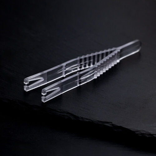 Klare sterile Triangel Piercingzange auf schwarzem Hintergrund, einzeln verpackt